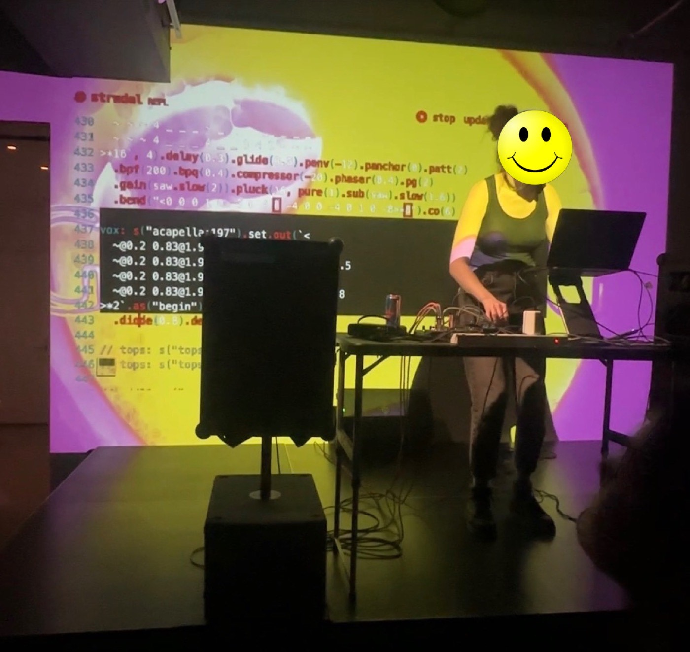 Performer running a live coded set through the sound system with visuals projected behind